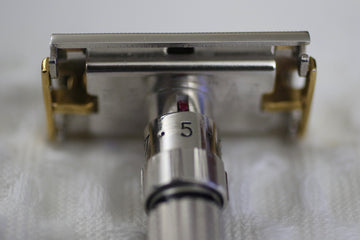 Adjustable safety razor with gold accents on a white surface.